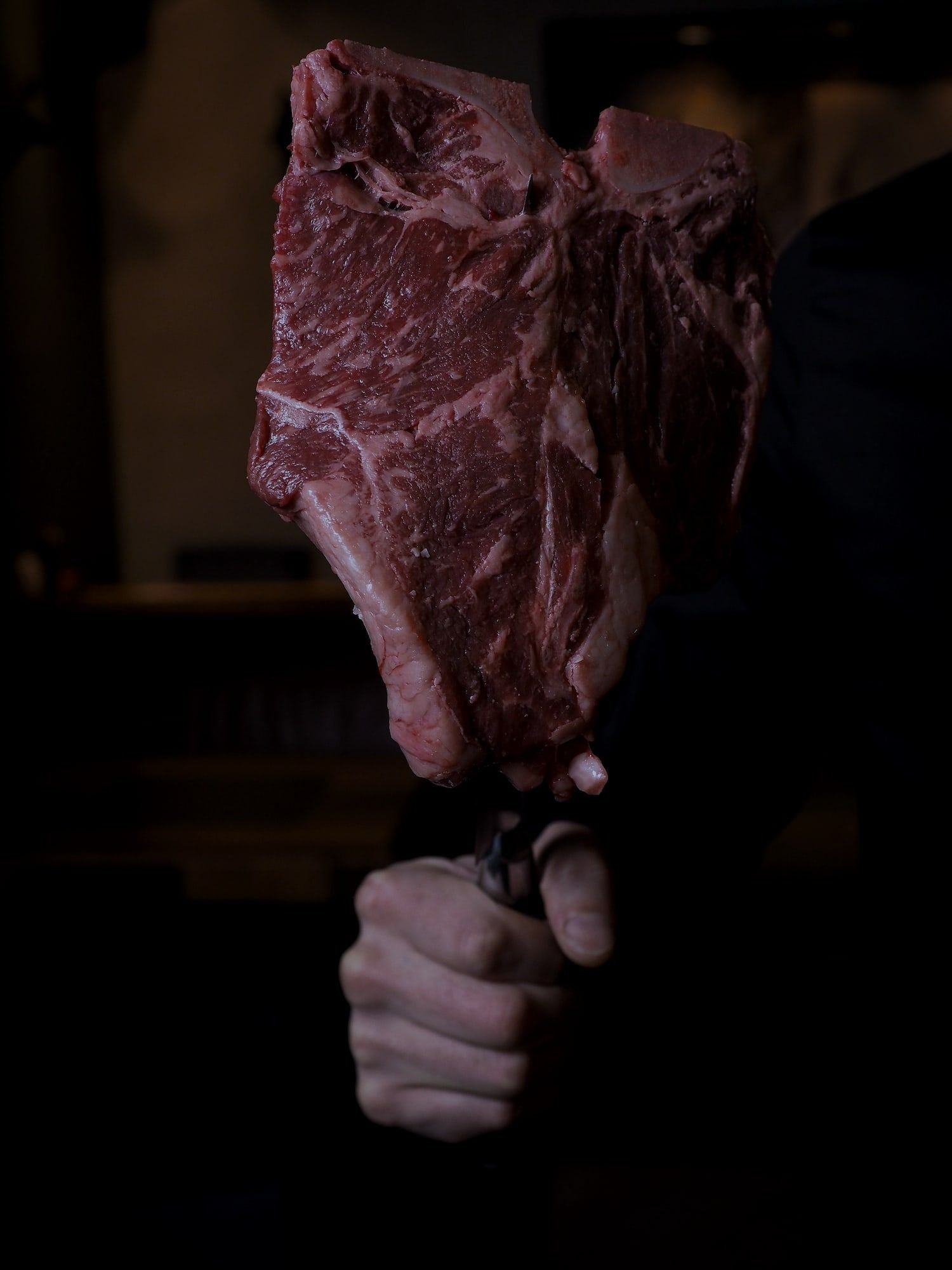 A bone-in beef loin held up on a carving fork